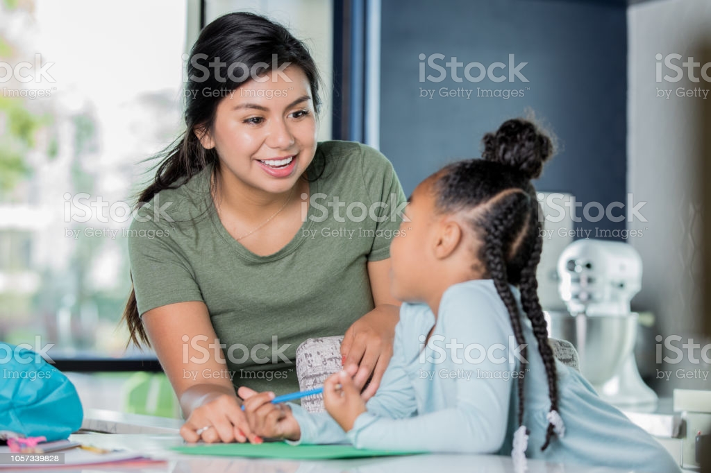 happy-young-hispanic-woman-is-babysitting-tutoring-elementary-age-picture-id1057339828